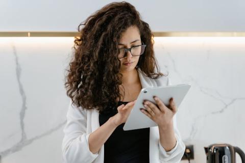 Woman typing on her iPad while standing.